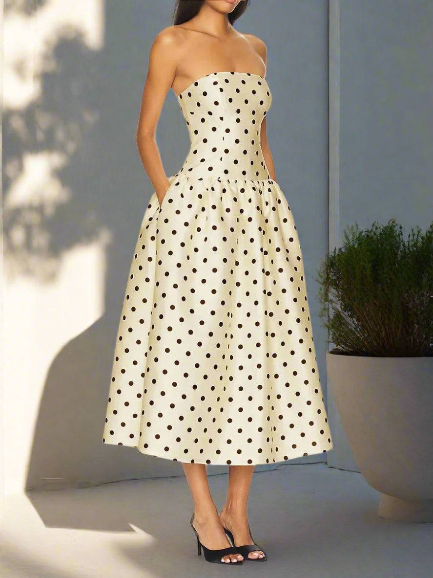 Woman wearing a strapless polka dot dress on a backyard, with sunlight