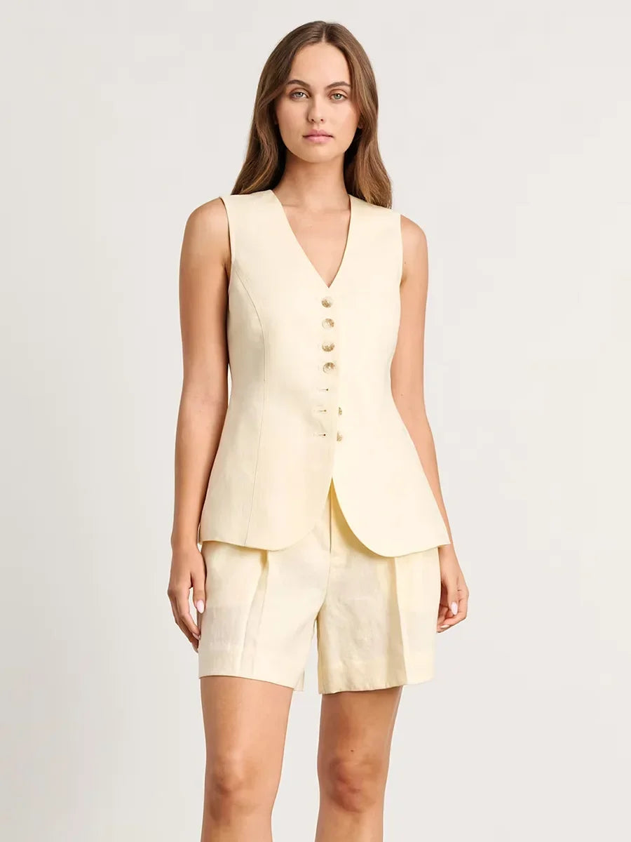 Woman wearing a light yellow sleeveless top and shorts set on a plain background