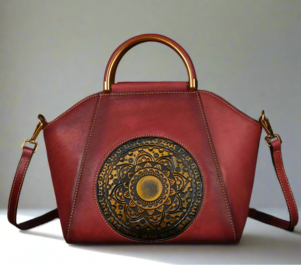 Red handbag with gold and black decorative emblem on a light background