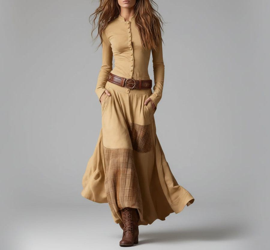 Woman wearing a long beige dress with plaid pattern and brown belt against a gray background