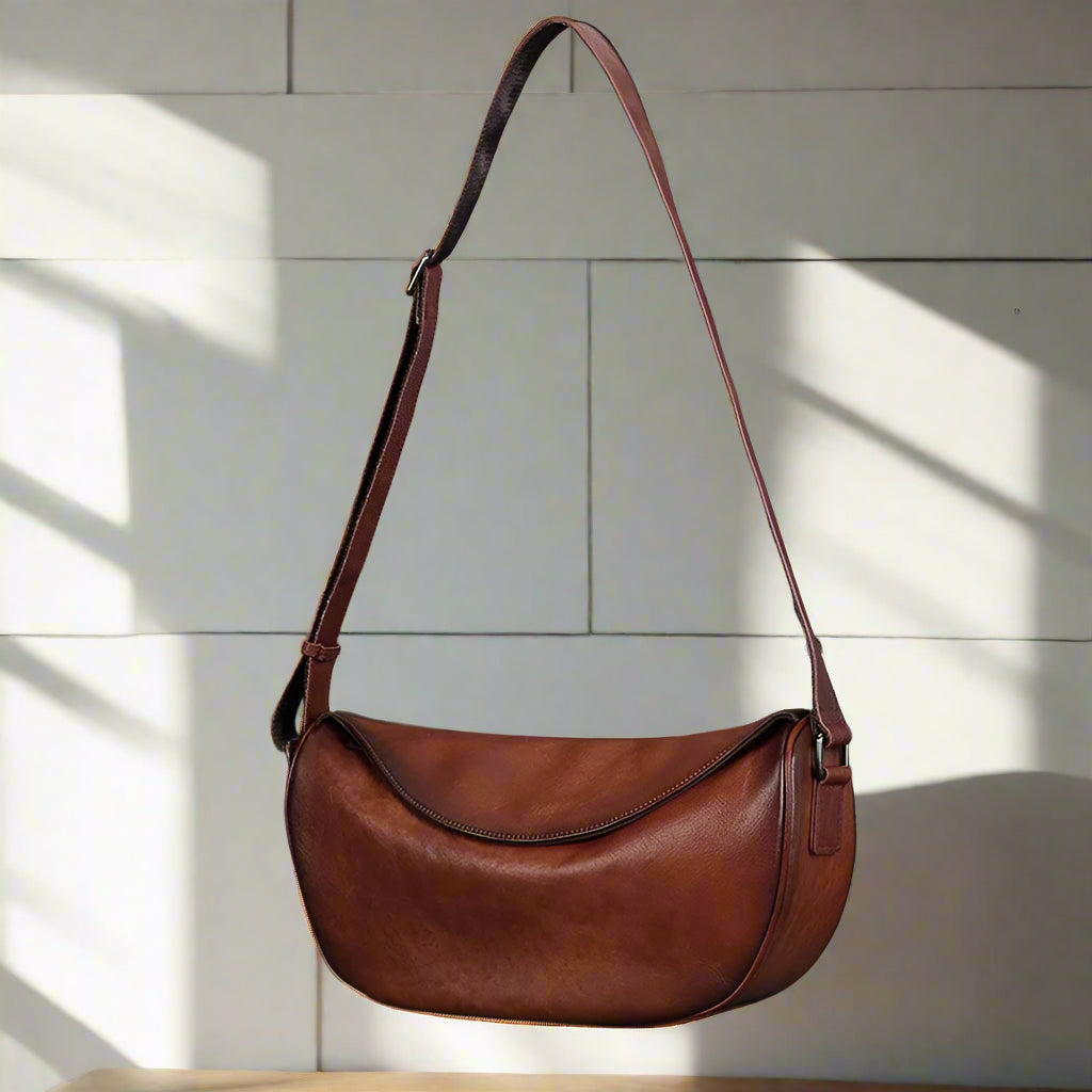 Brown leather shoulder bag on light background