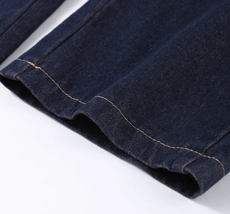 Close-up of dark blue denim fabric with visible stitching on a white background