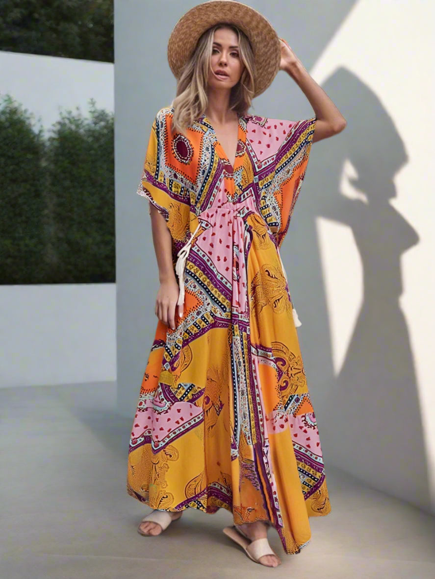 Woman wearing a colorful patterned dress and straw hat in a garden setting