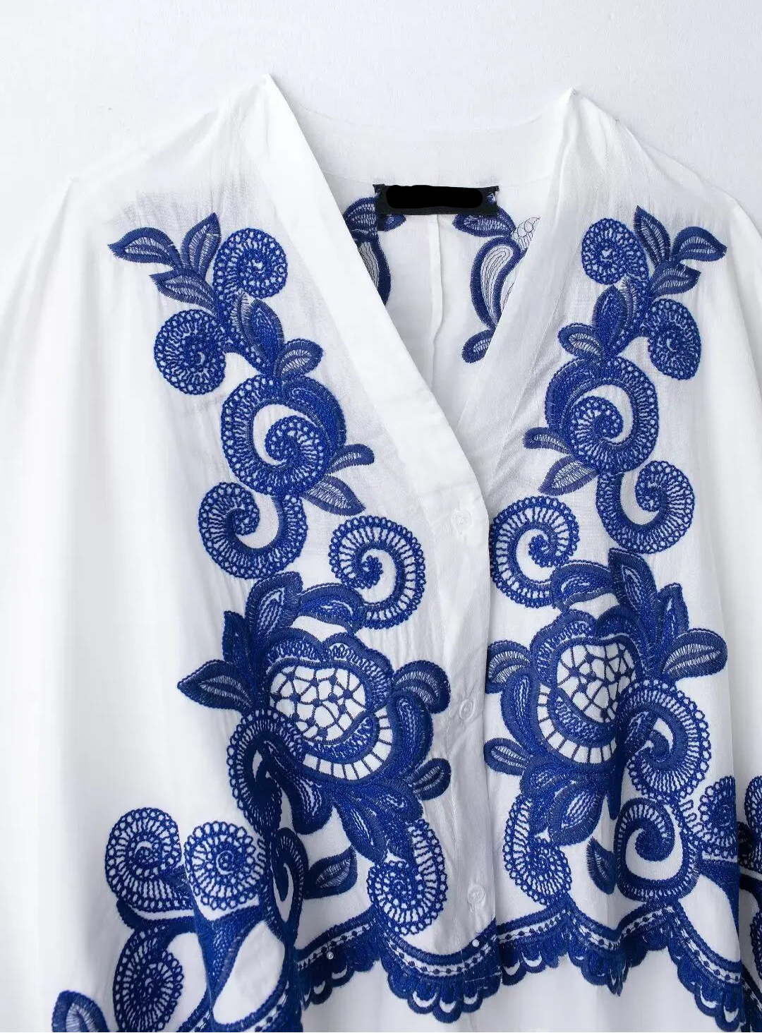 White garment with blue floral embroidery on a white background