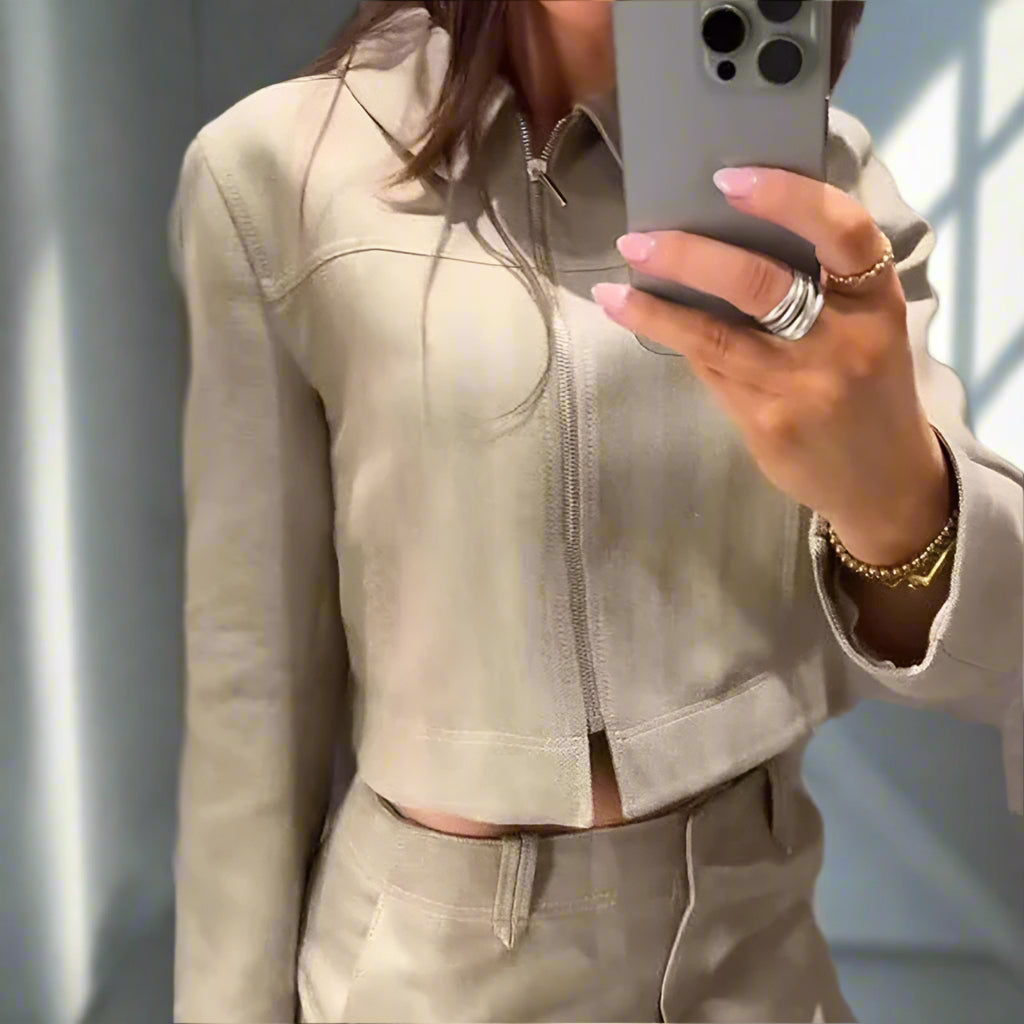 Person wearing a beige jacket taking a mirror selfie.