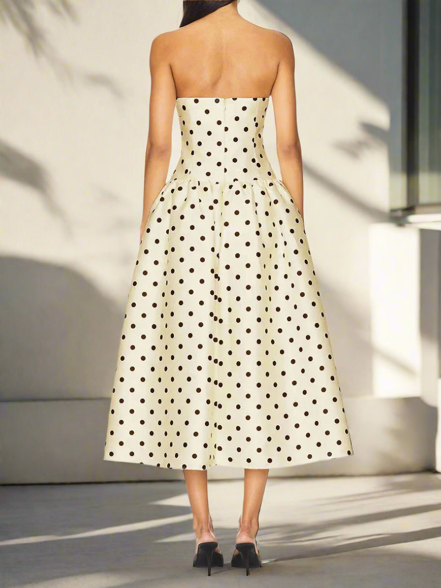 Woman wearing a strapless polka dot dress, back view of the dress, on a backyard and sunlight
