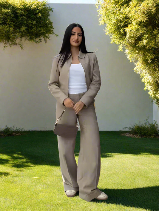 Woman in a beige outfit standing outdoors with a backyard garden, sunny