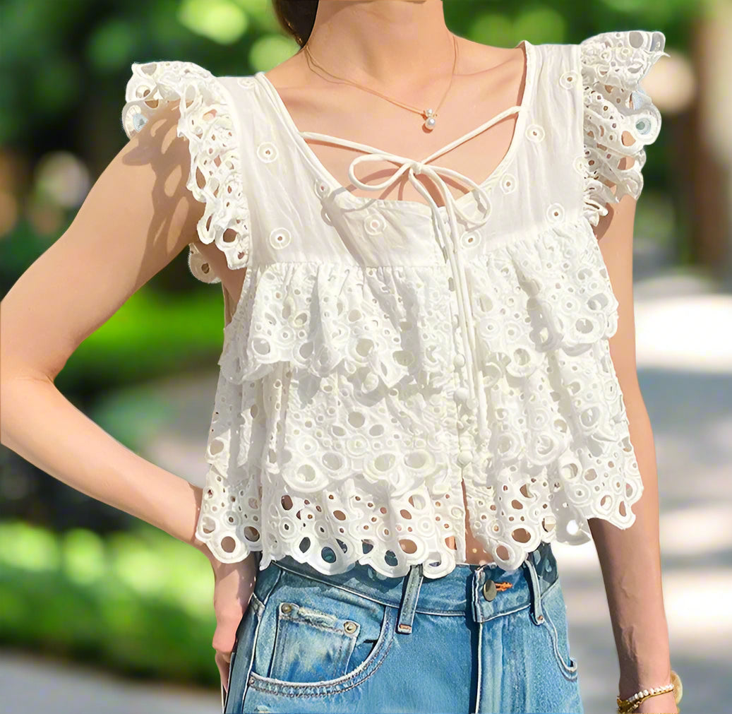 White lace top worn by a person with a backyard garden, sunny