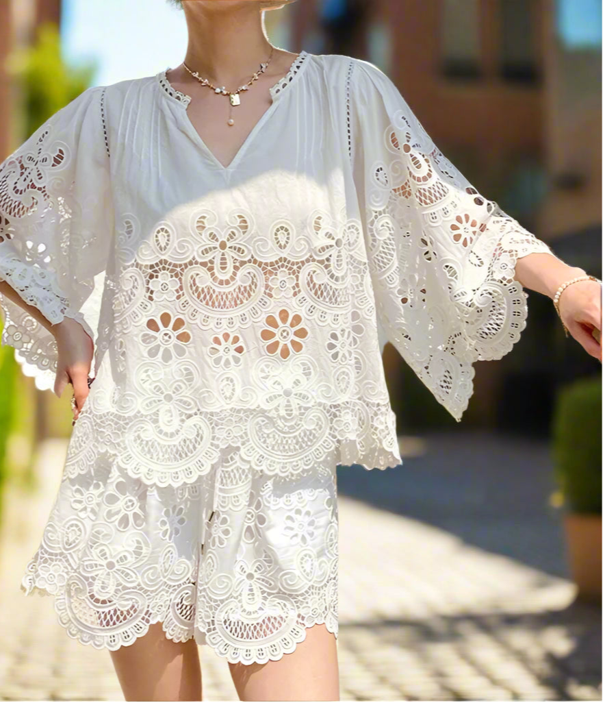Person wearing a white lace dress standing in front of a backyard garden, sunny