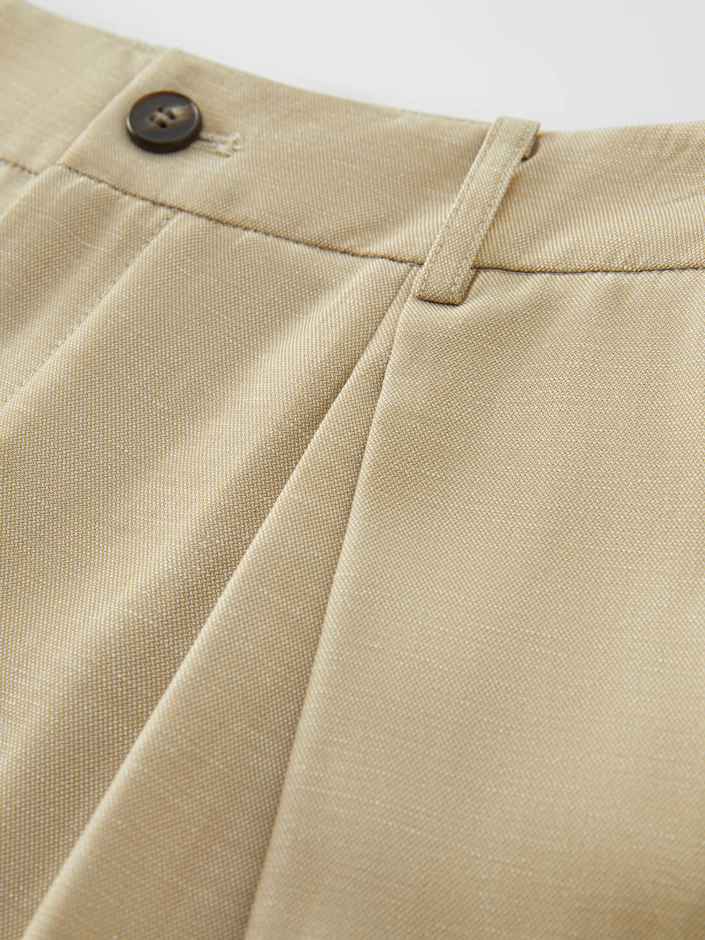 Close-up of beige pants with a button on a white background
