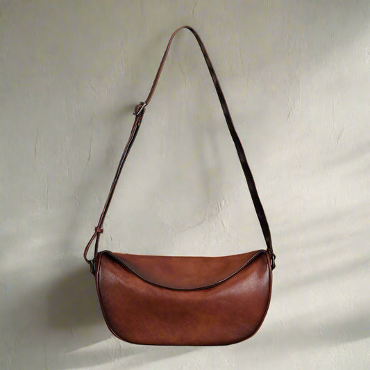 Brown leather bag with a strap on a glight background