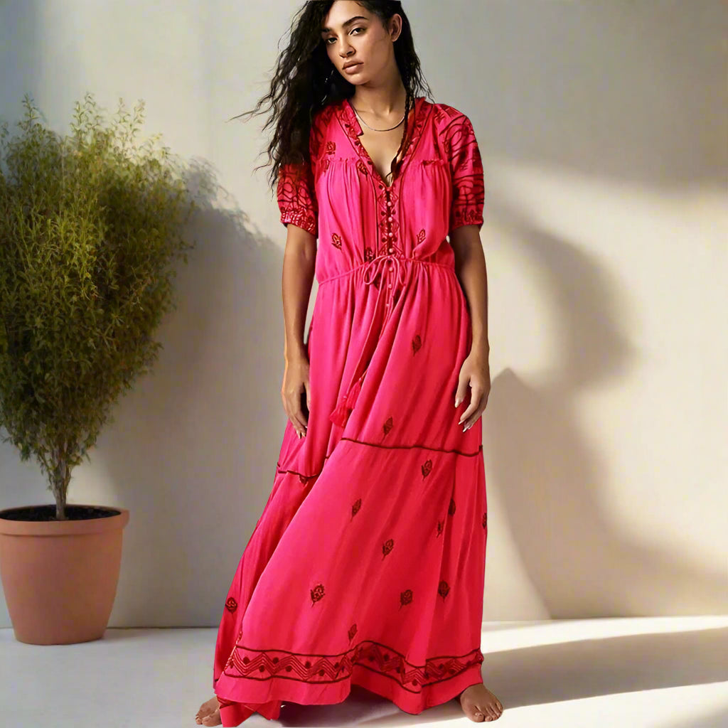 Woman wearing a bright pink dress with black patterns on a white background