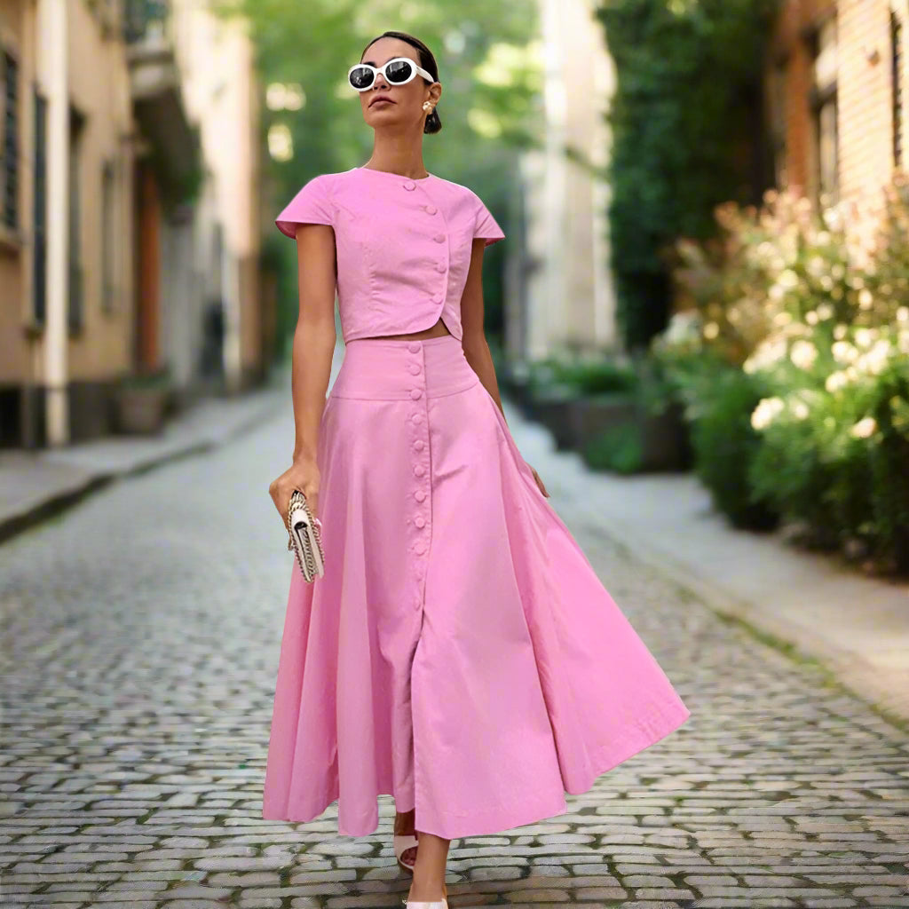 Woman wearing a pink outfit standing against a backyard garden