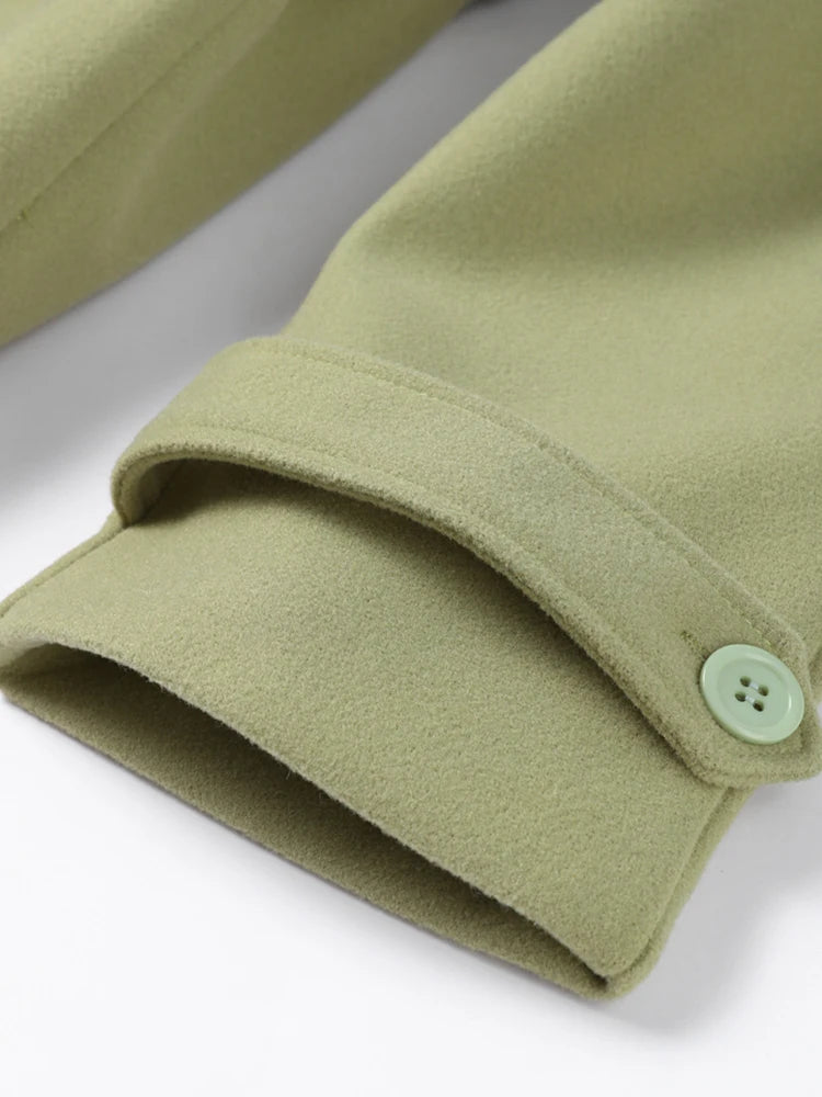 Close-up of green fabric with a button on a white background