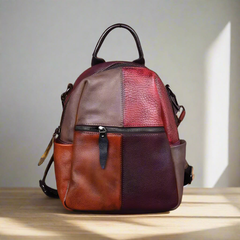 Multicolored patchwork backpack on a wooden table with a white wall background