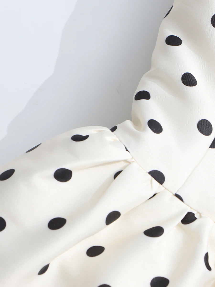 Close-up of a white fabric with black polka dots on a plain background