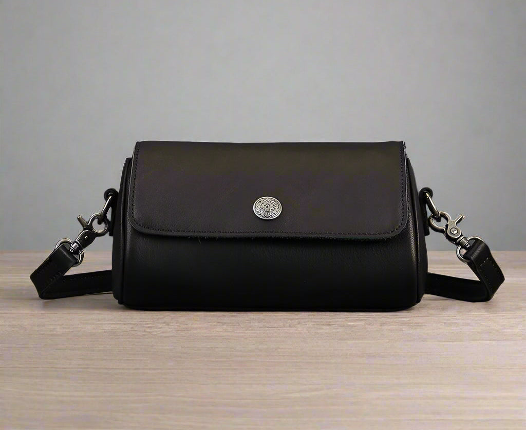 Black leather handbag with a silver clasp on a wooden surface