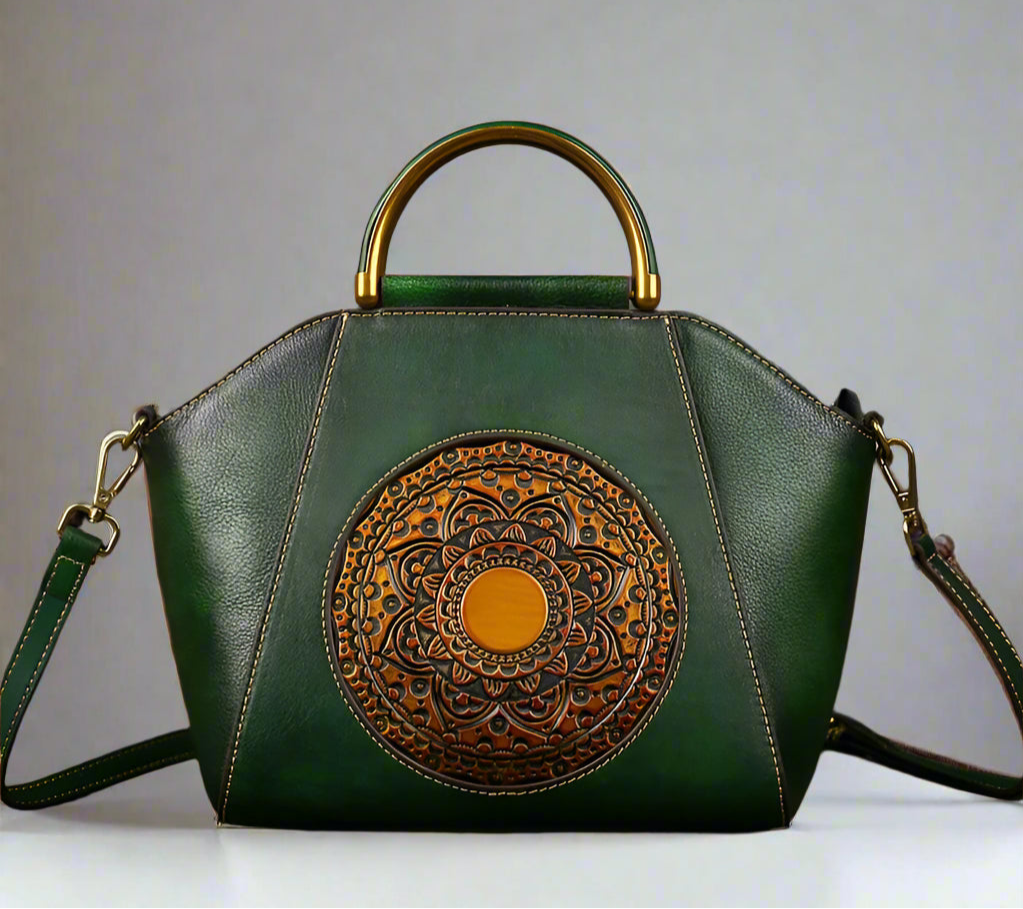 Green handbag with gold handle and decorative circular emblem on a light background