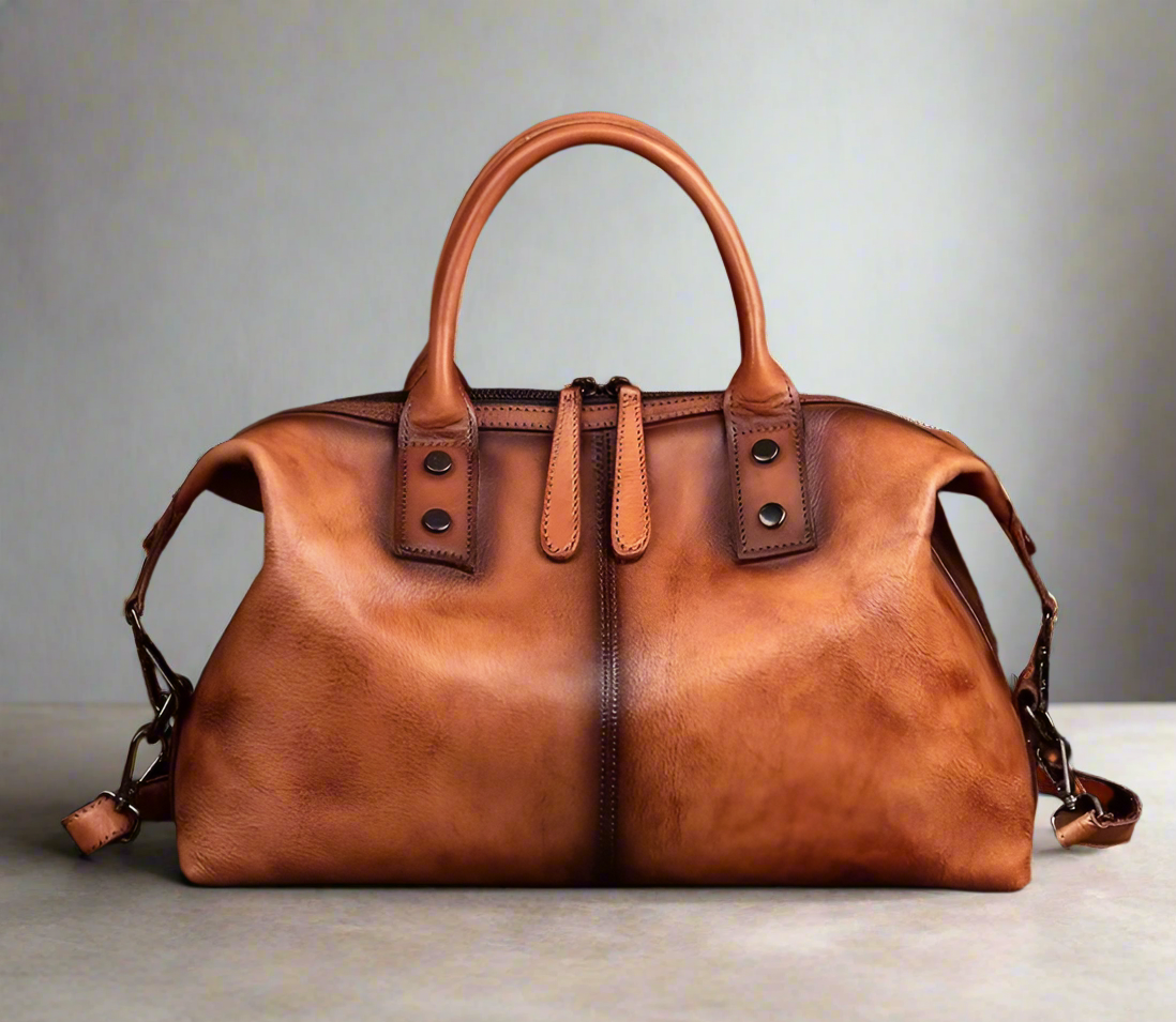 Brown leather handbag on a wooden surface with a white background